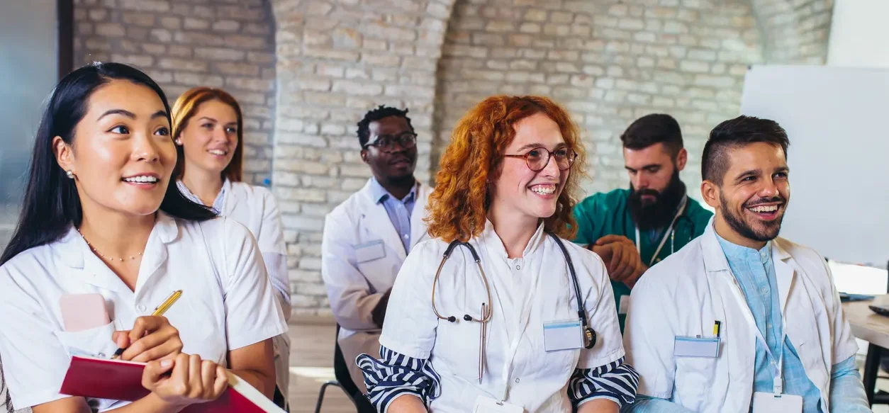 six OUM students in scrubs taking notes